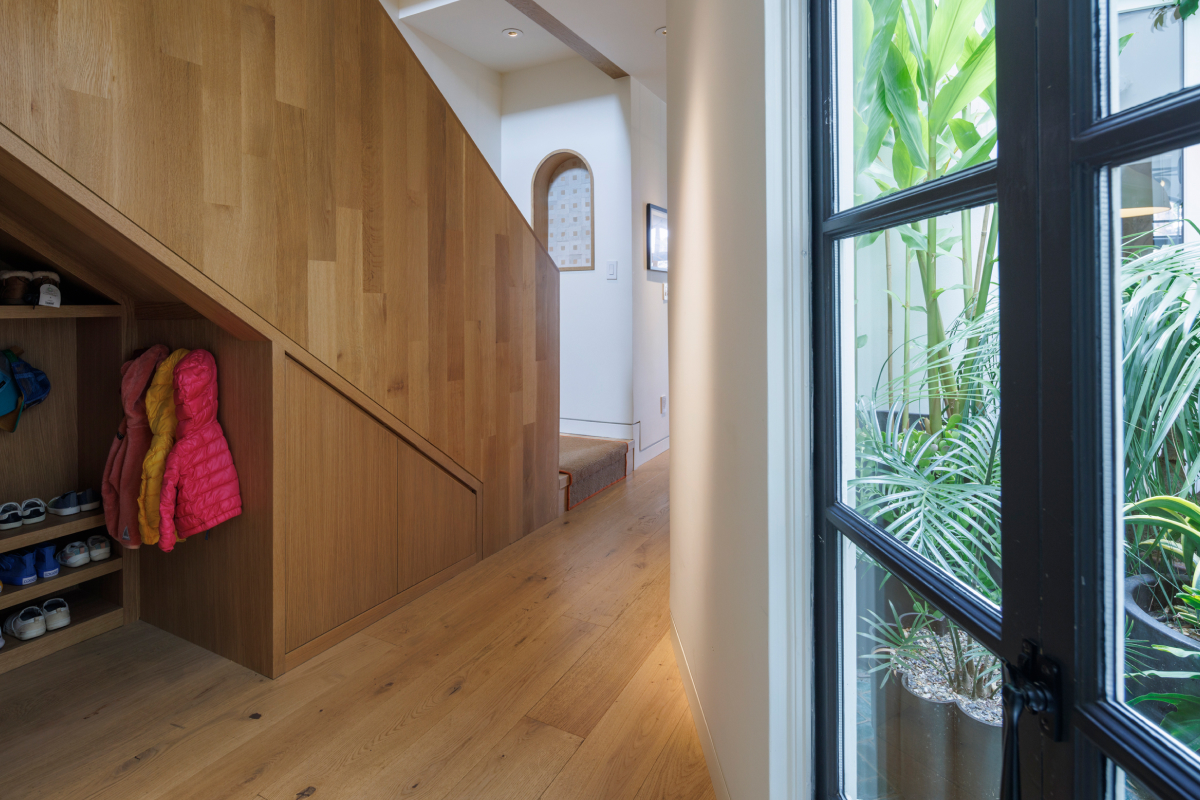 Noe Valley Addition and Renovation Hallway with Wood Panel Stairway and Lush Plants Seen Through Window
